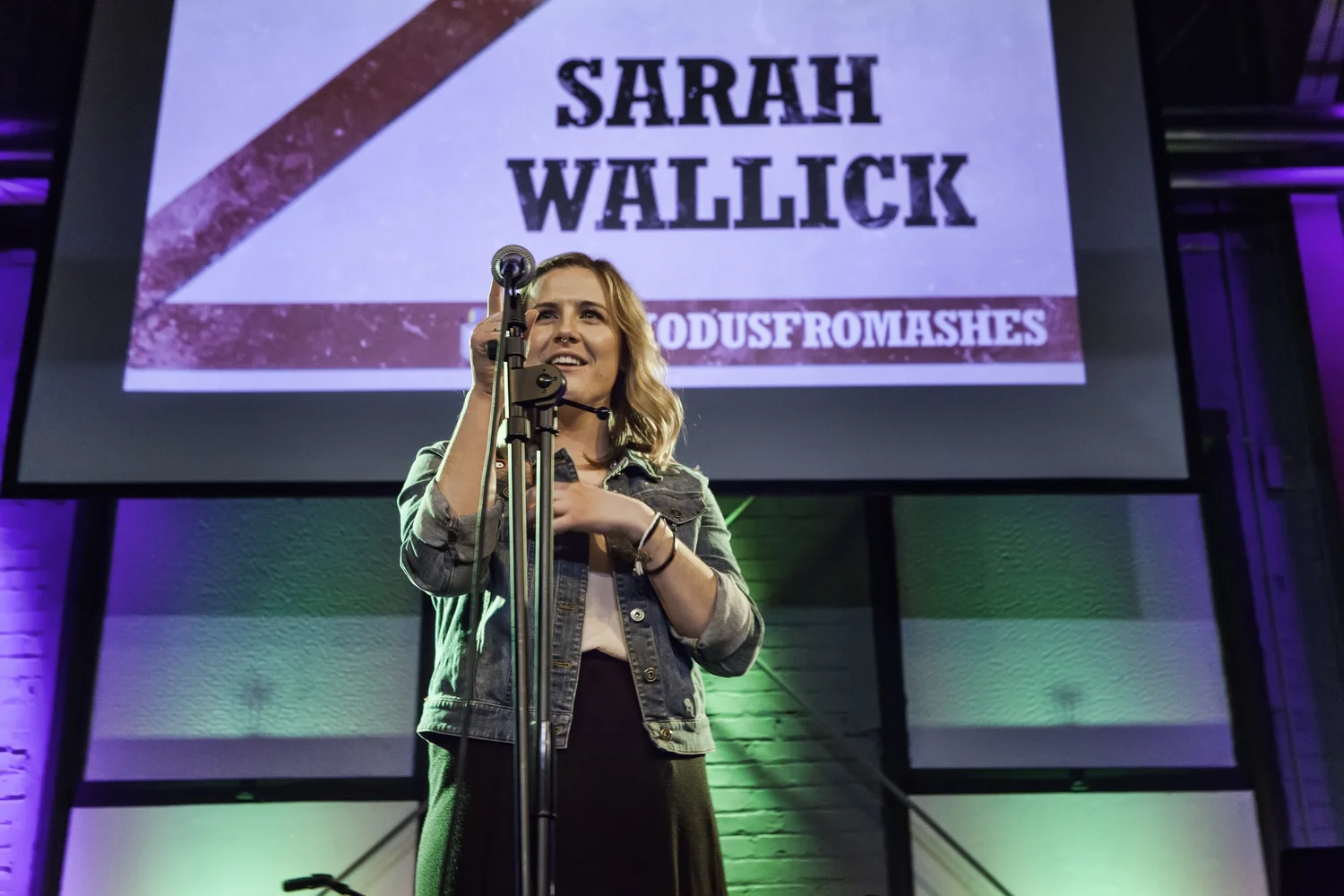 Close view of a vocalist beneath a Sarah Wallick projection.