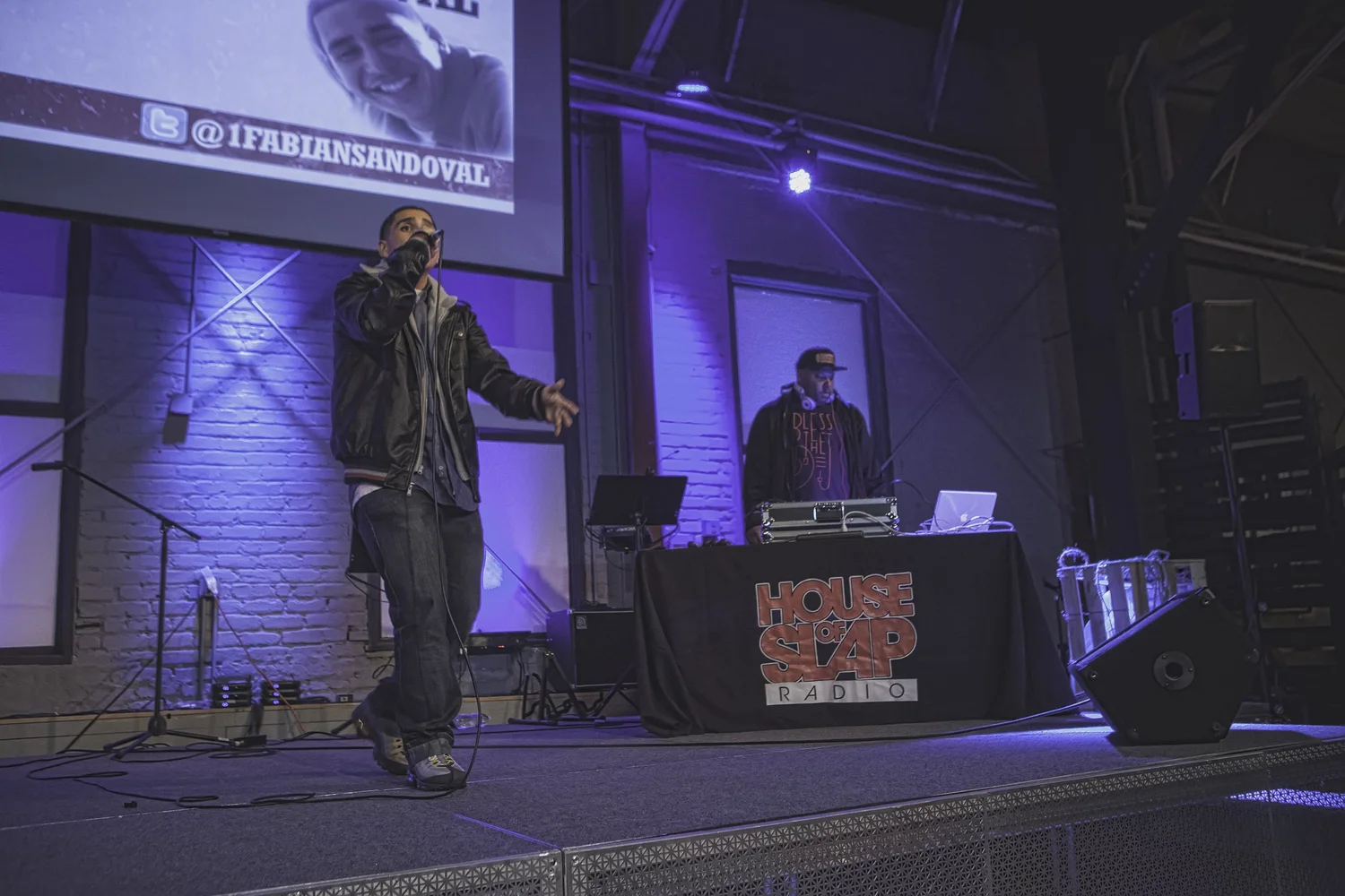 Vocalist and DJ beneath purple stage lighting.