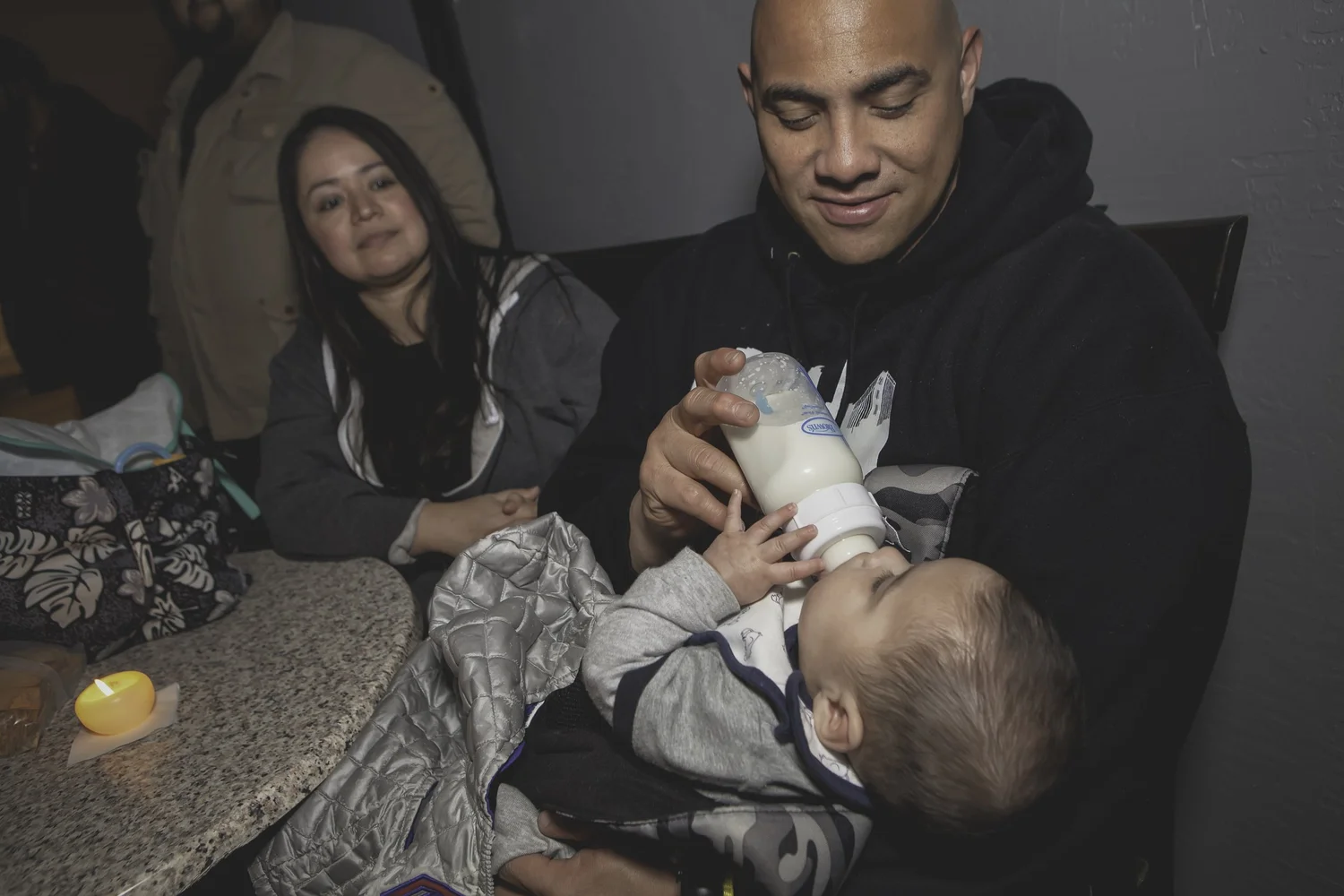 Adult bottle-feeding a baby in the audience.