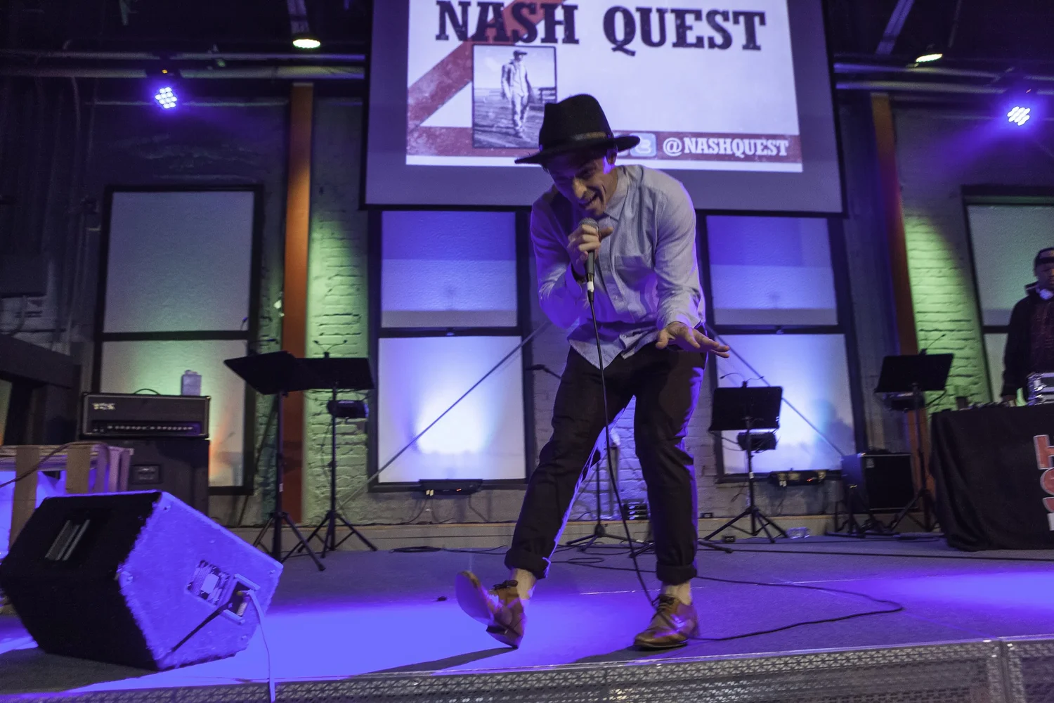 Performer moving beneath a Nash Quest projection.
