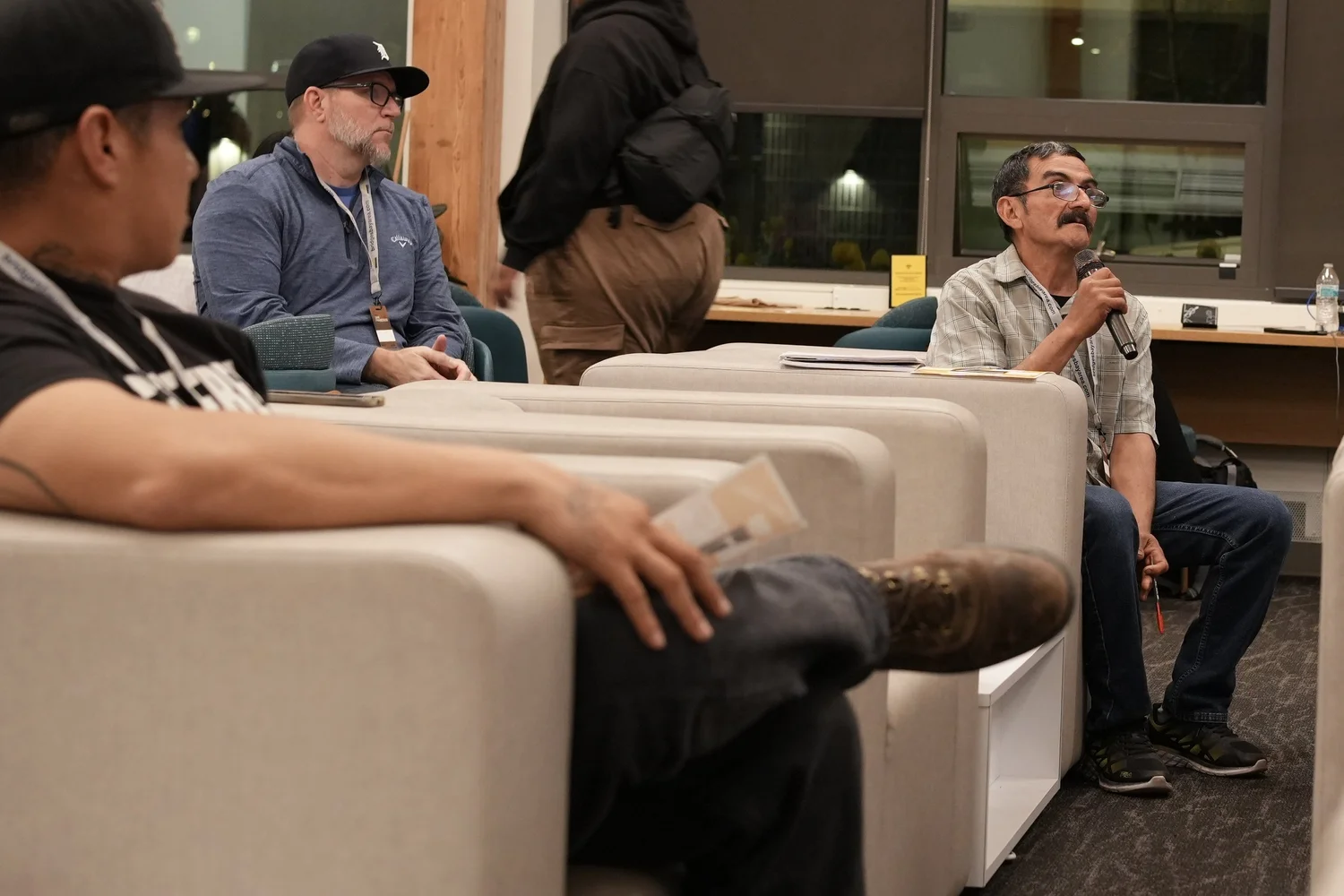 A seated participant speaks into a handheld microphone.