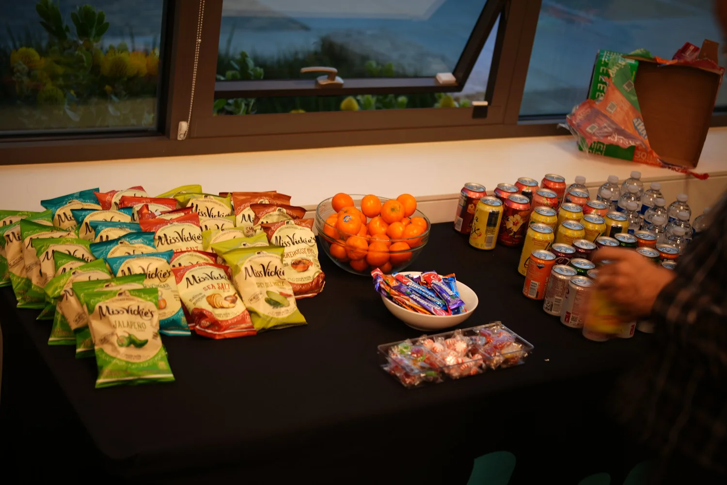 Packaged snacks, fruit, and drinks arranged on a refreshments table.