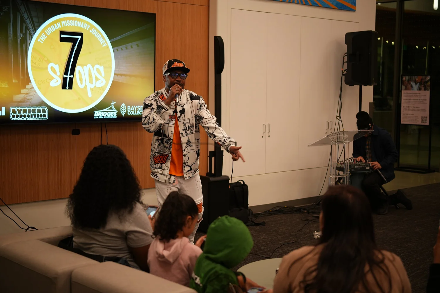 A performer speaks into a microphone during the community gathering.