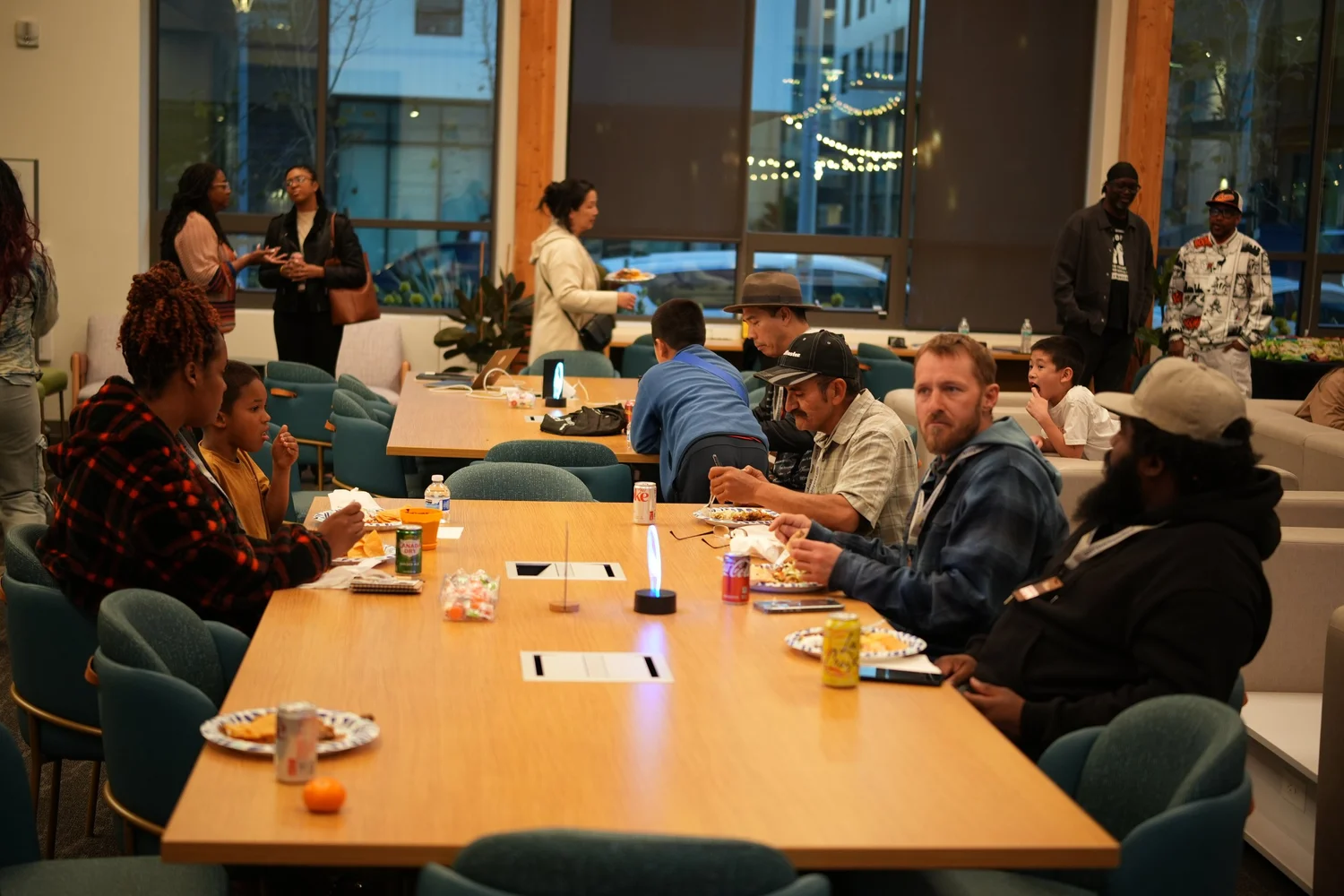Guests seated around tables and sofas listen to the community program.