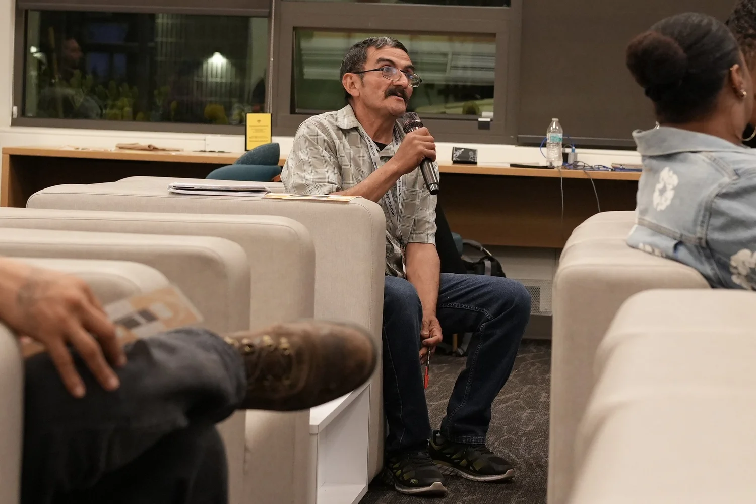 A seated participant speaks into a handheld microphone.