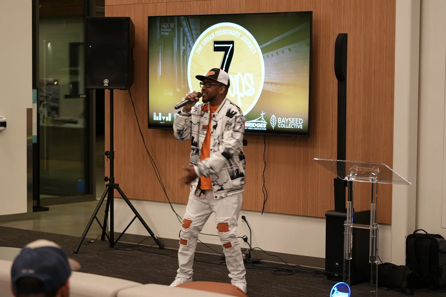 Performer in a patterned outfit in front of the event screen.