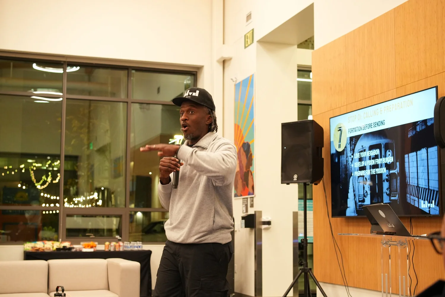 Performer in a light sweatshirt gesturing toward the audience.