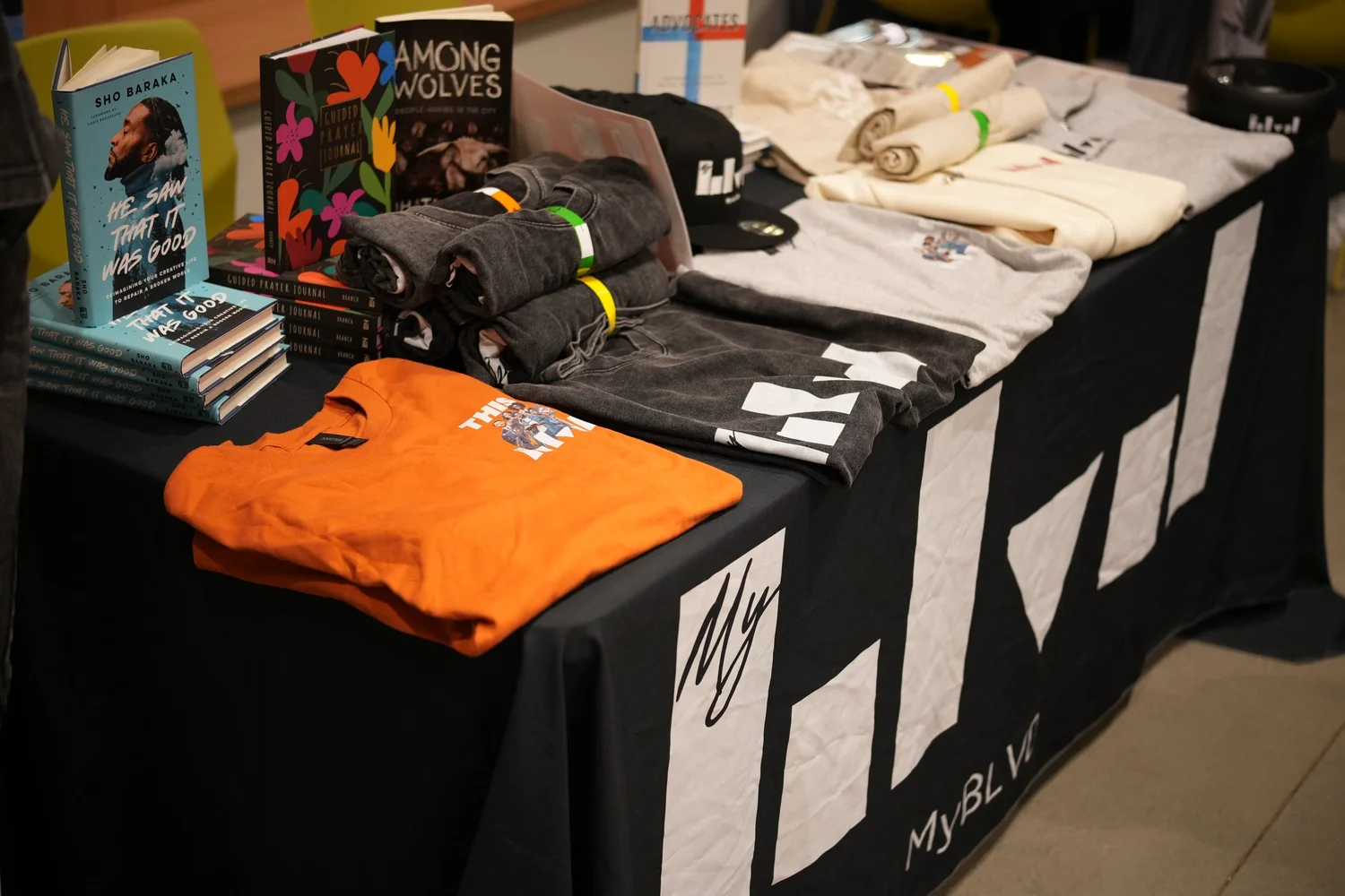 Books, shirts, and other merchandise arranged on a display table.