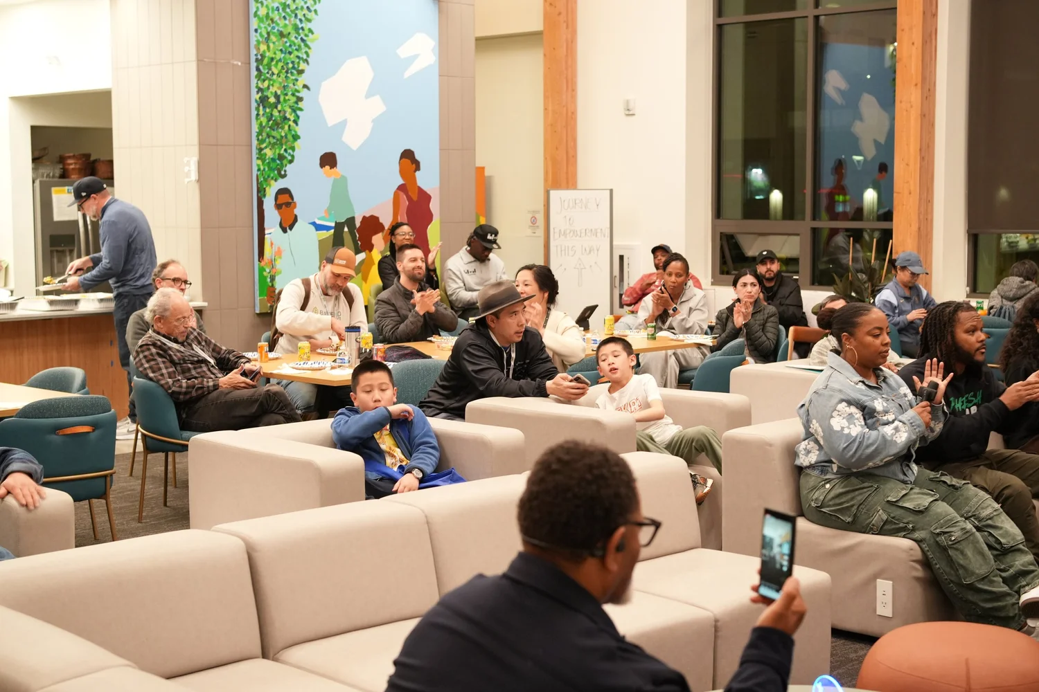 Families and community members seated throughout the lounge.