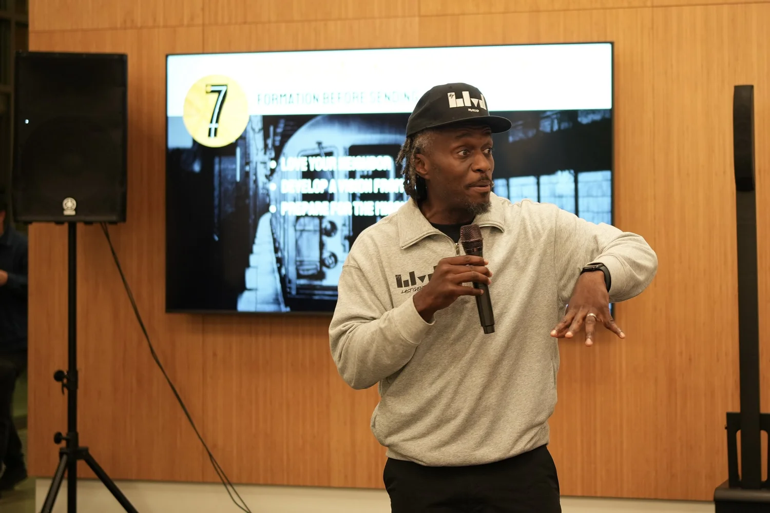 Performer gesturing in front of the event screen.