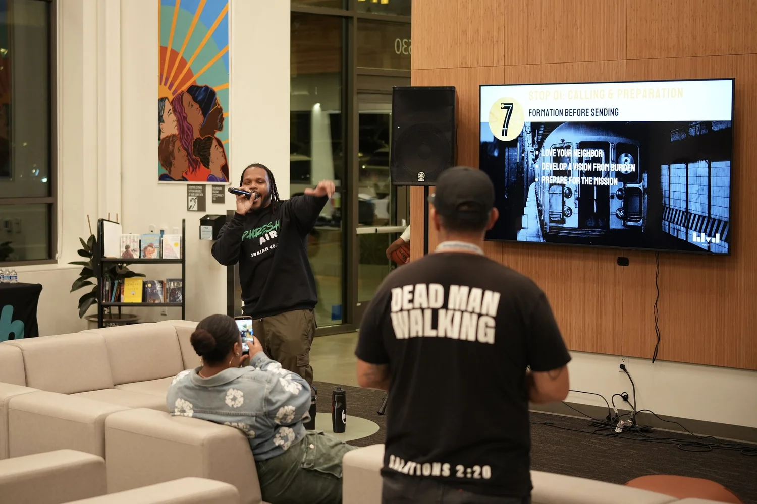 Performer addressing attendees from beside the event display.