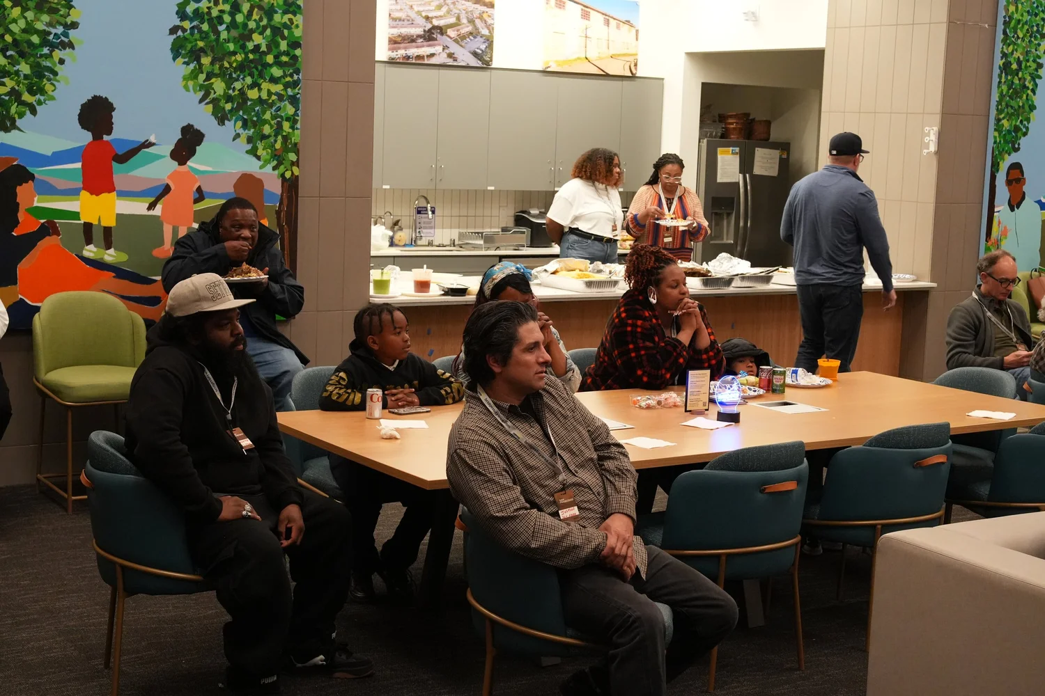 Guests seated around a table beneath a community mural.