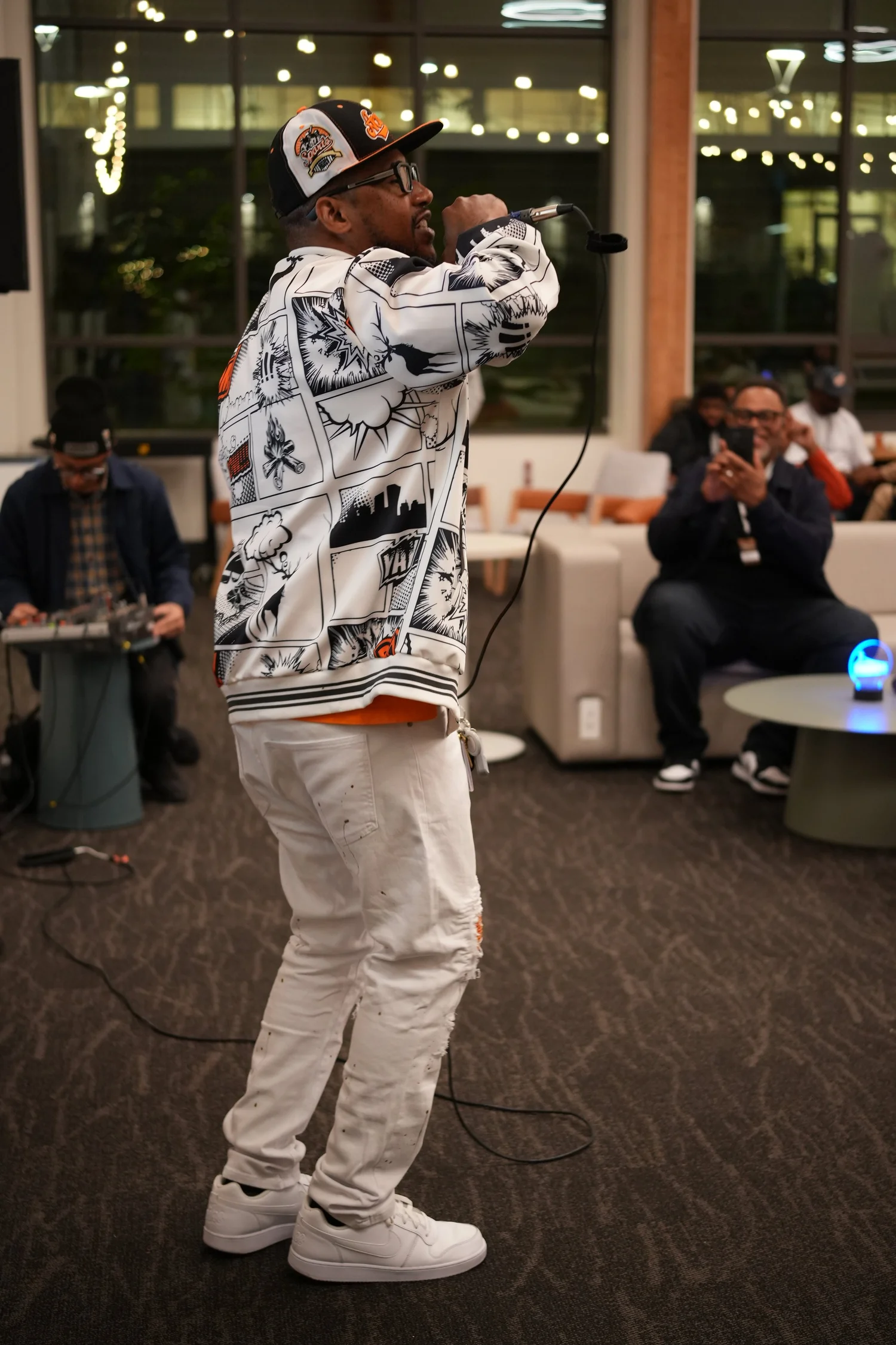 Full-length view of a performer in a patterned jacket and white pants.