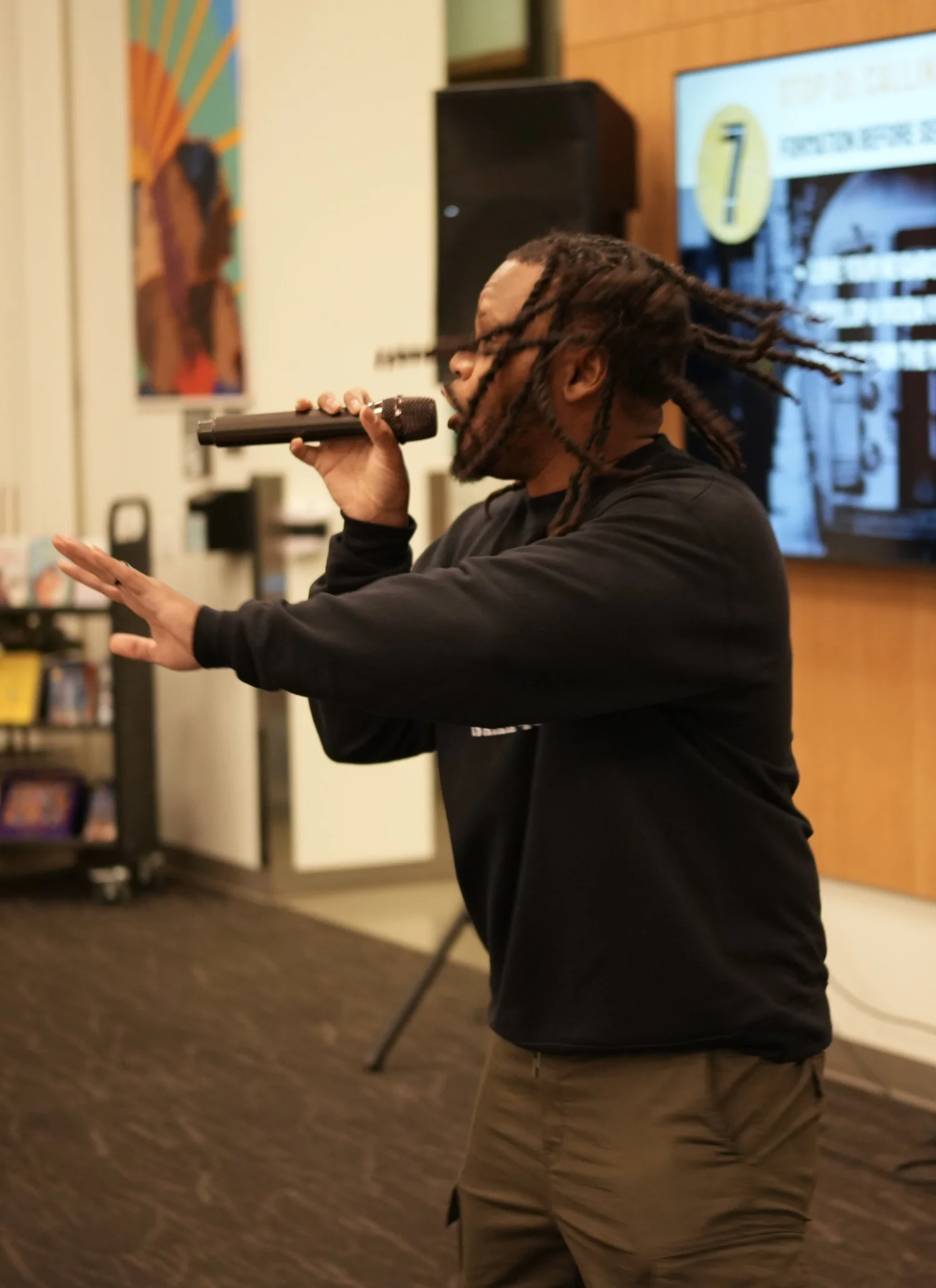 Performer extending a hand while singing into a microphone.