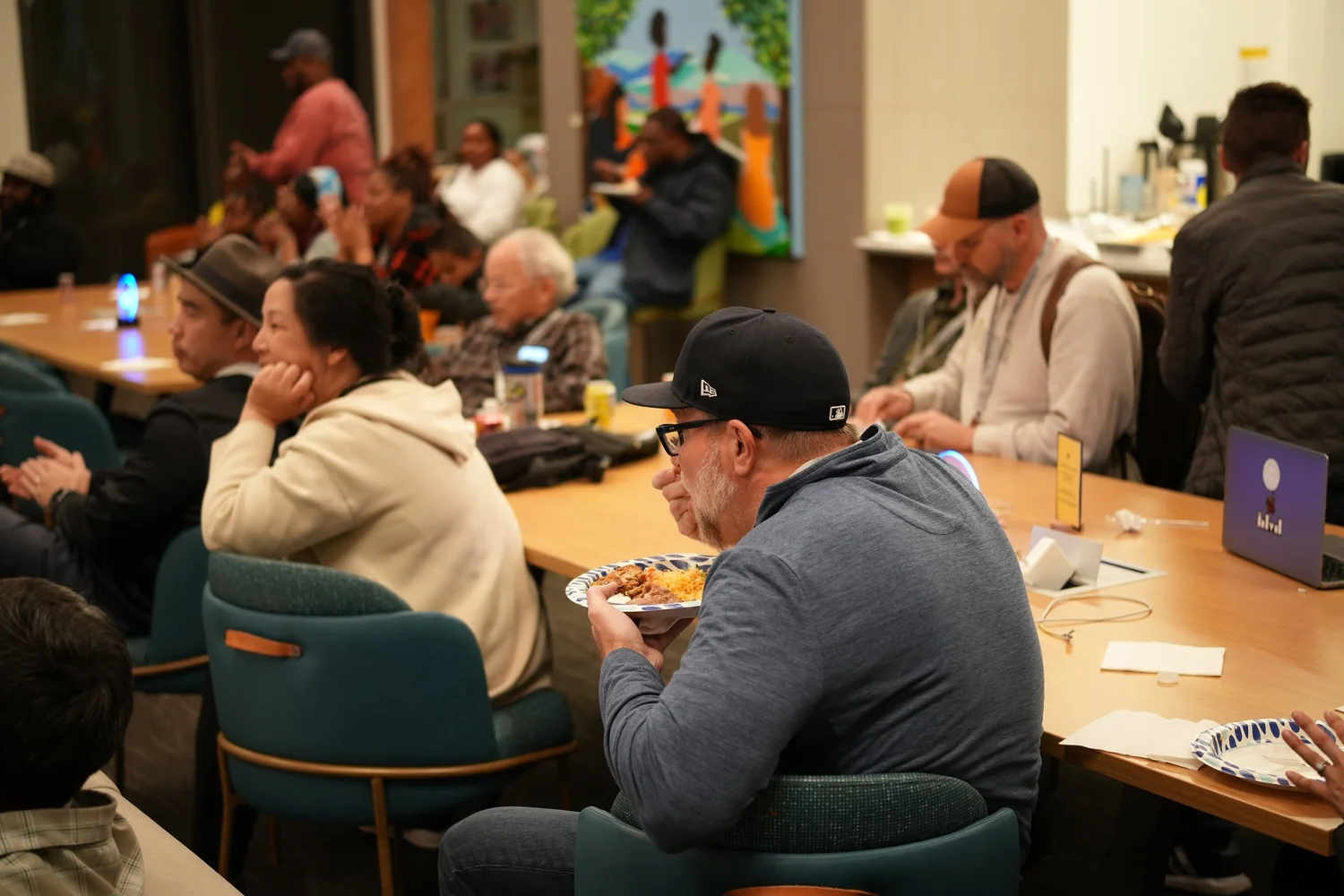Guests eating and listening around a long table.