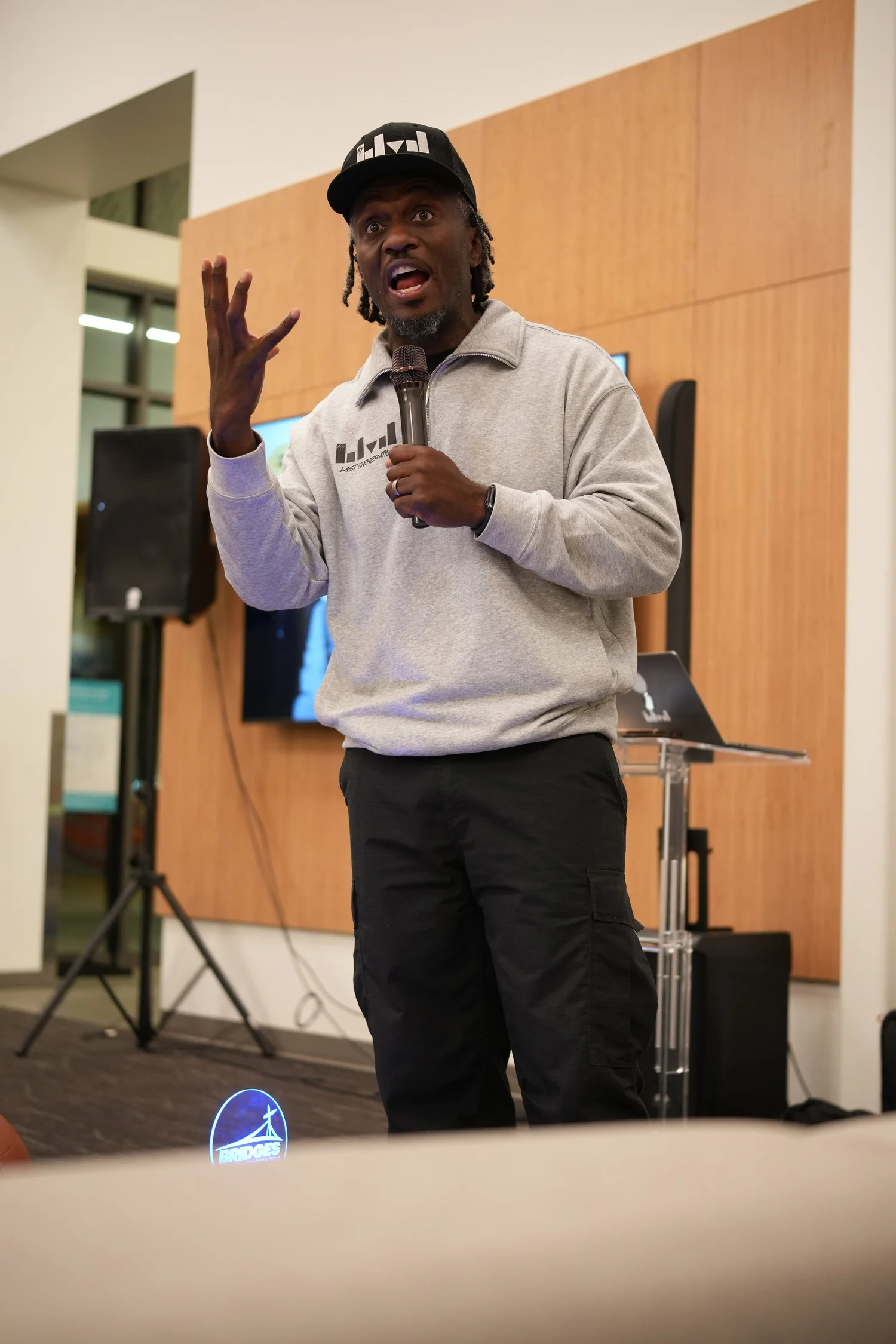 Speaker in a light sweatshirt raising a hand.