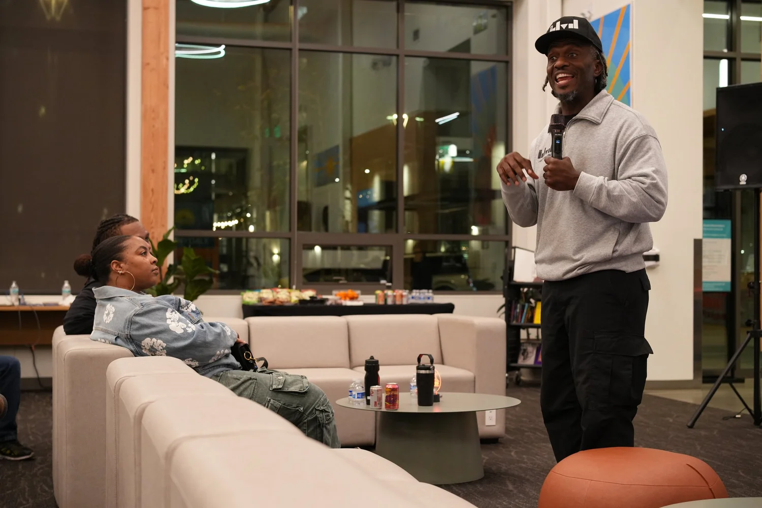 Speaker beside a seated attendee on a lounge sofa.