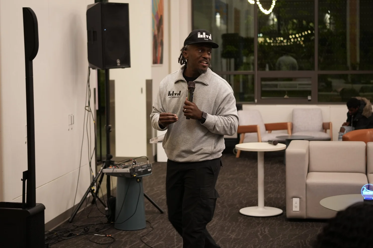 Speaker in a light sweatshirt holding a microphone beside the lectern.