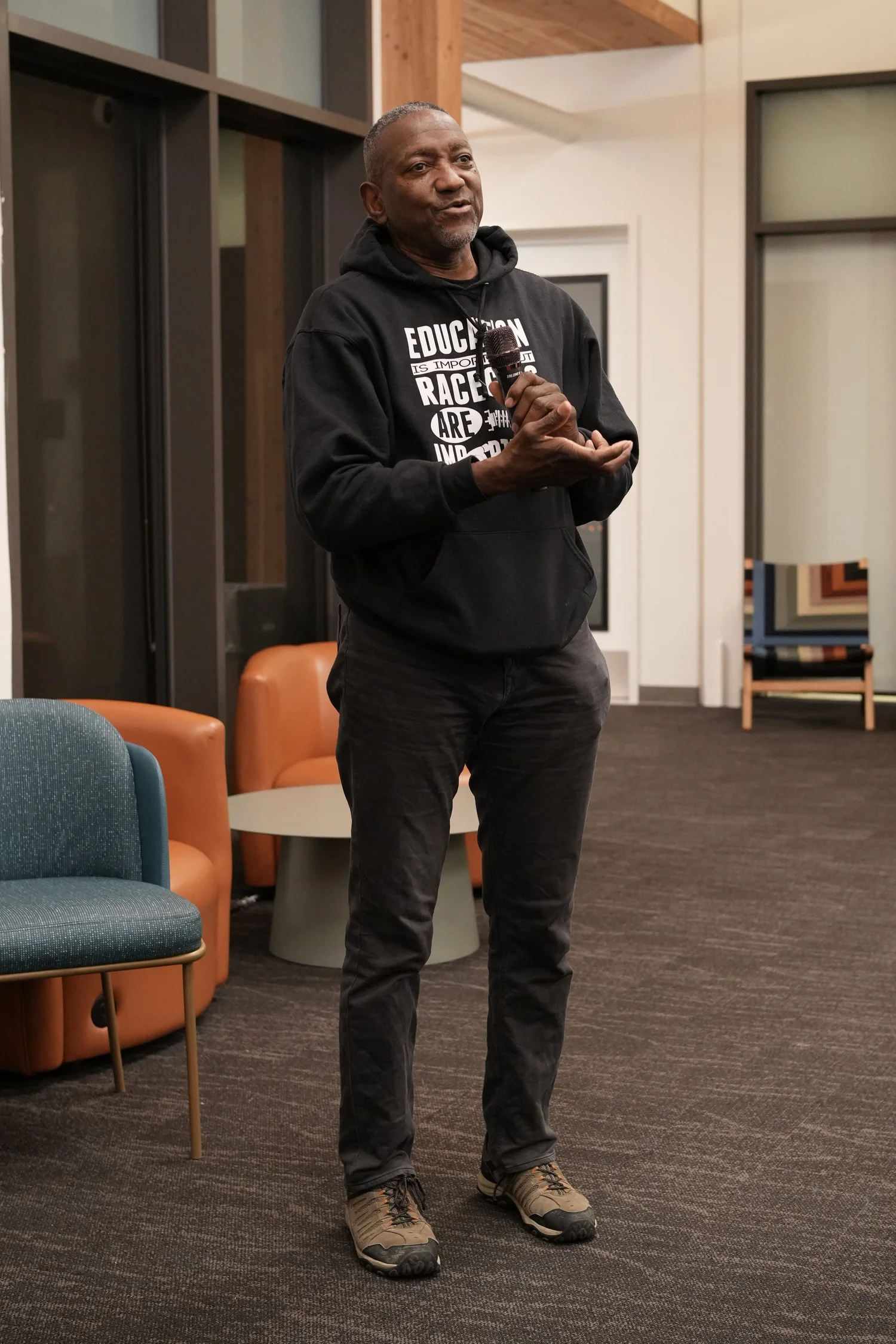 Attendee standing in a dark hoodie with hands together.