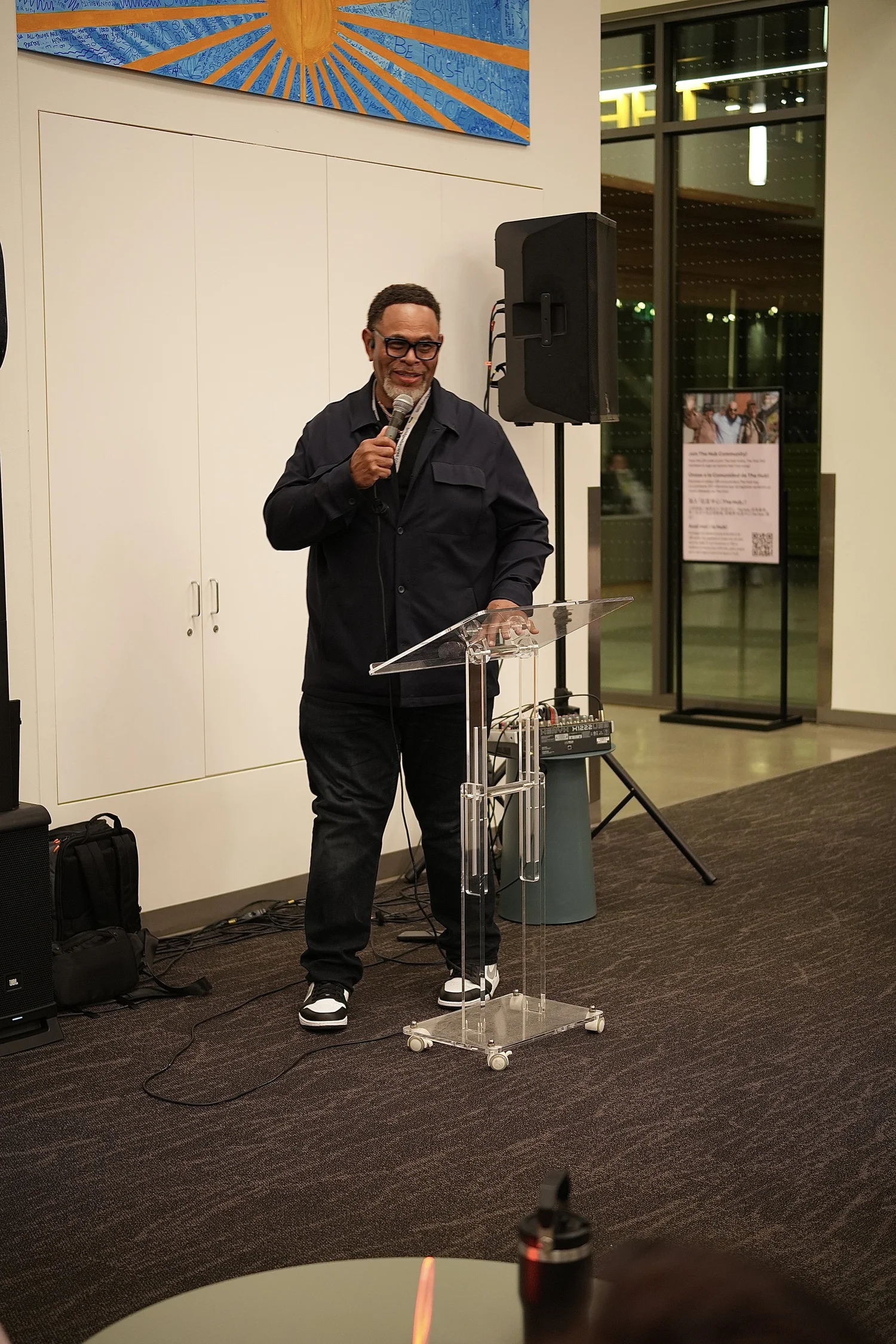 Speaker holding a microphone beside the clear lectern.
