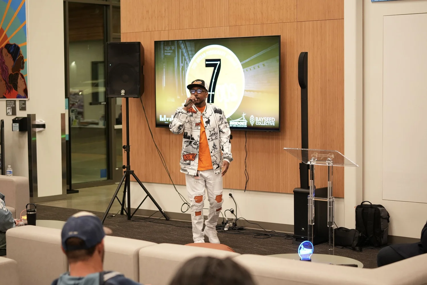 Full-length view of a performer beside a clear lectern.