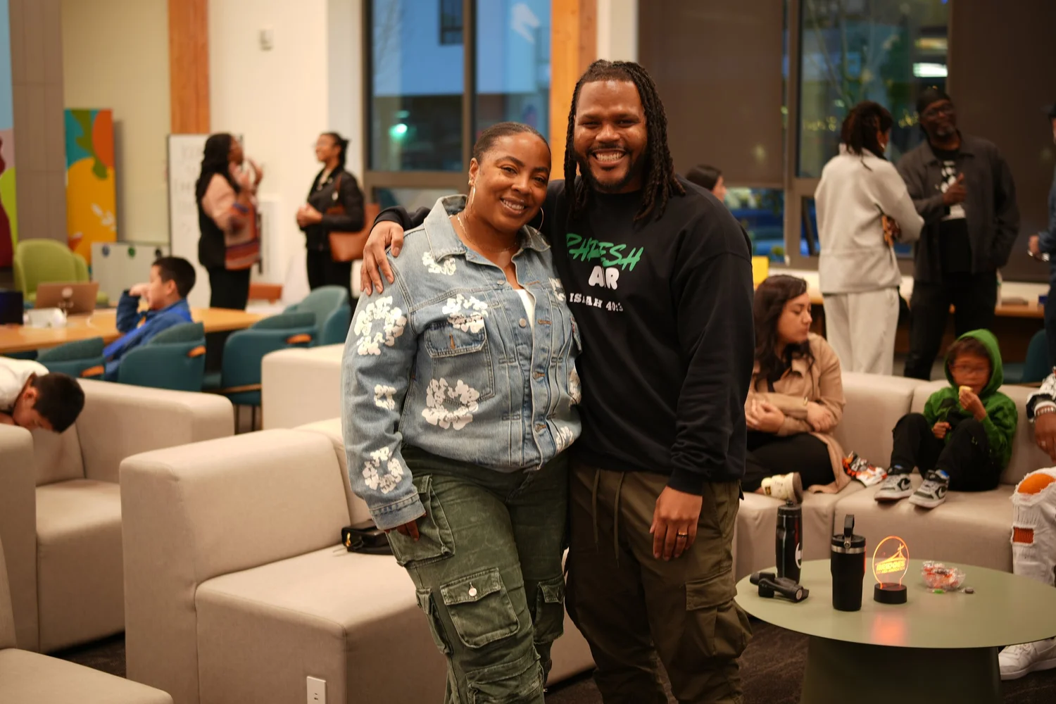 Two participants smiling together beside a sofa.