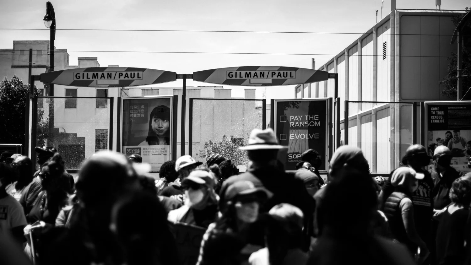Black-and-white view of the crowd near the Gilman/Paul transit stop.