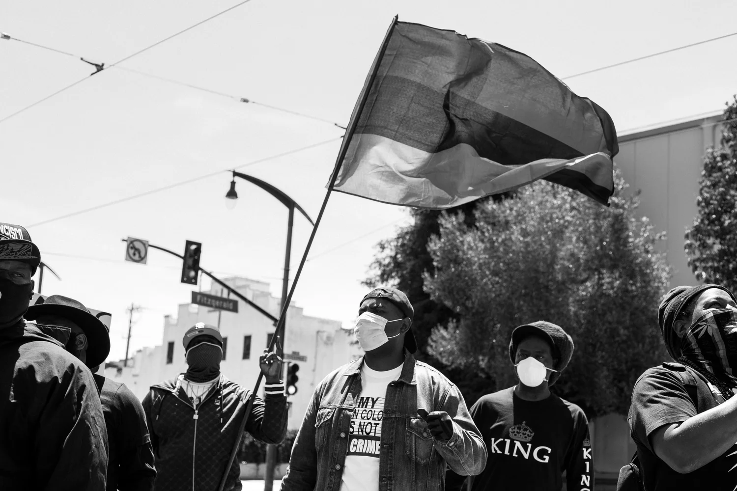 Black-and-white view of participants beneath a large flag.