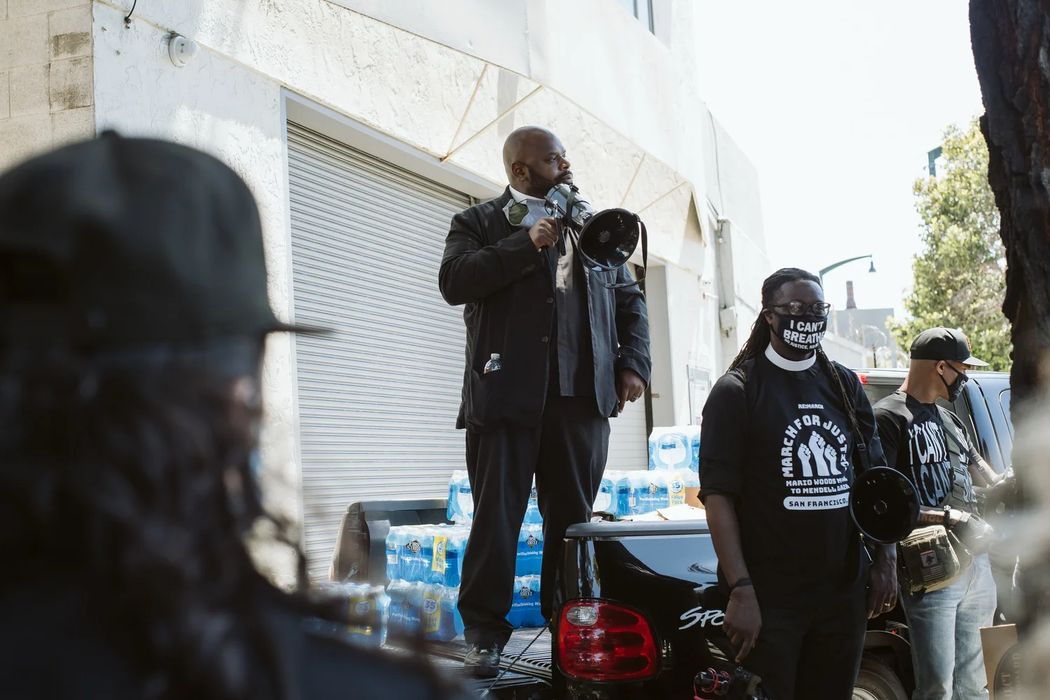 Speaker using a megaphone beside other rally participants.