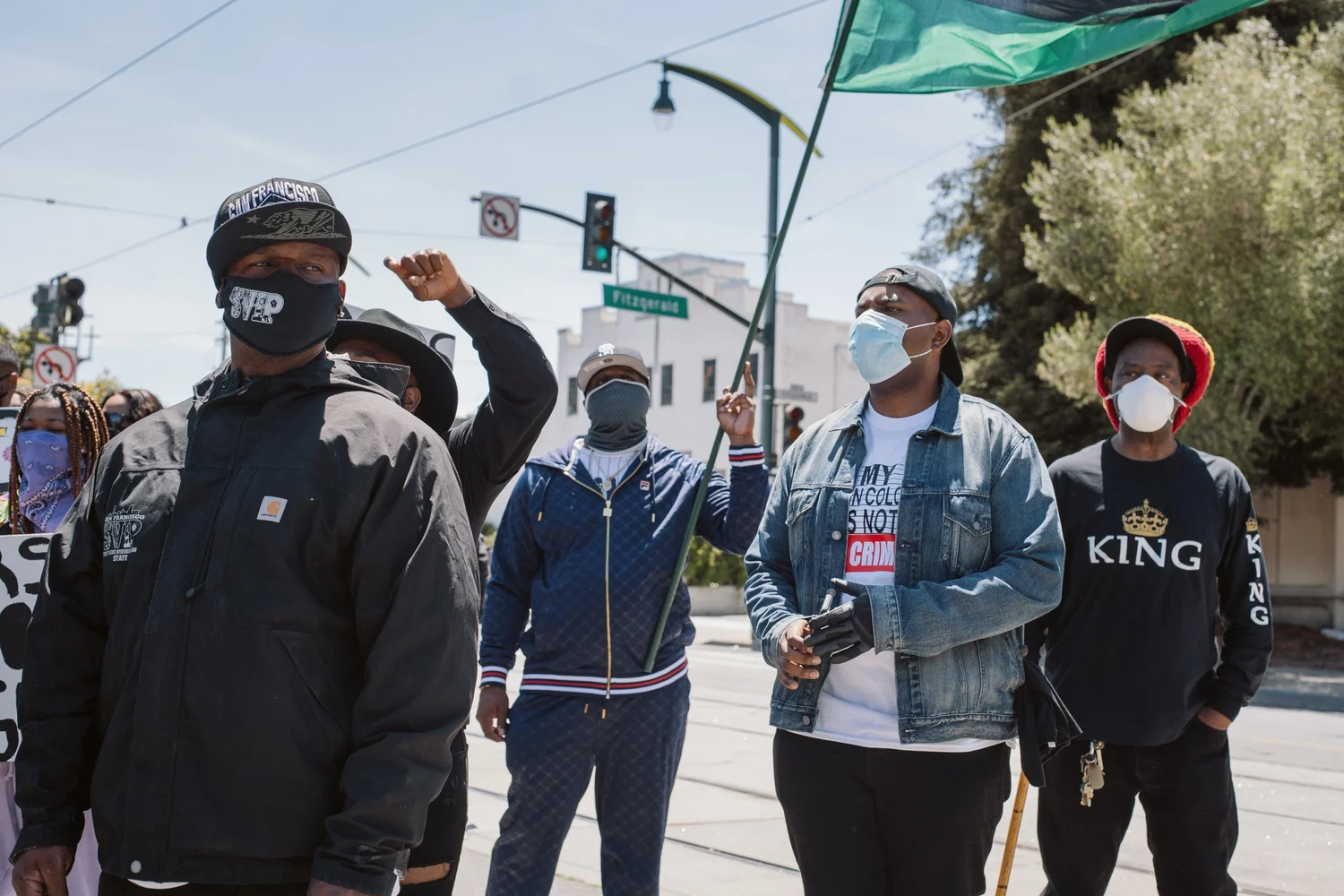 Masked participants standing beneath a raised flag.