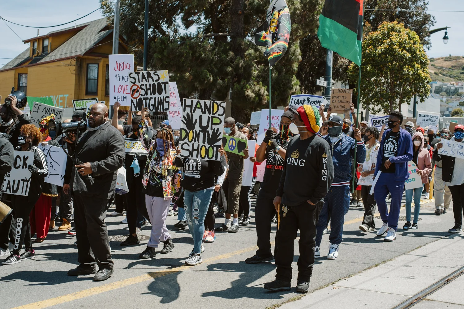Marchers carrying protest signs and flags along the street.