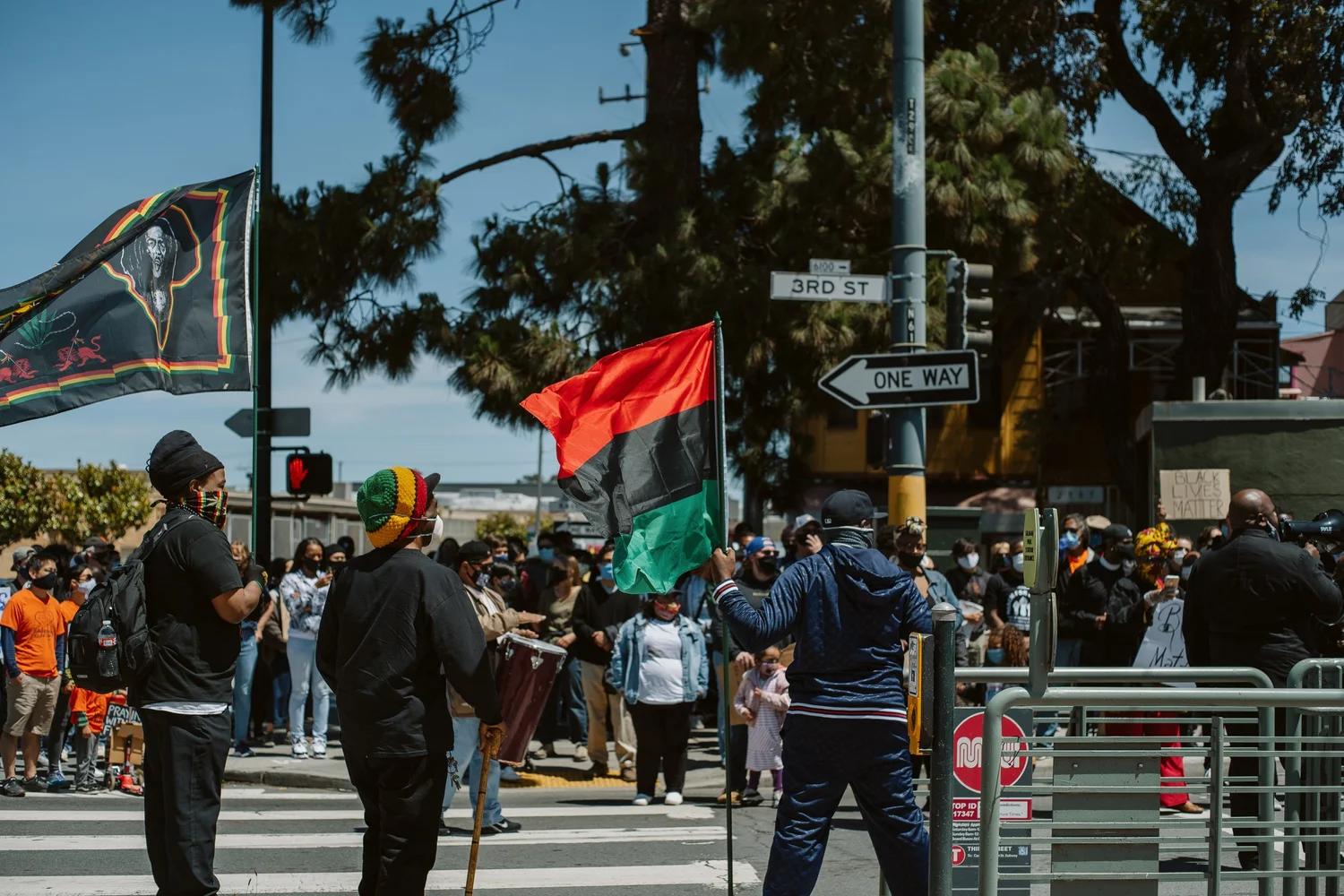 Crowd gathering at the intersection beneath raised flags.