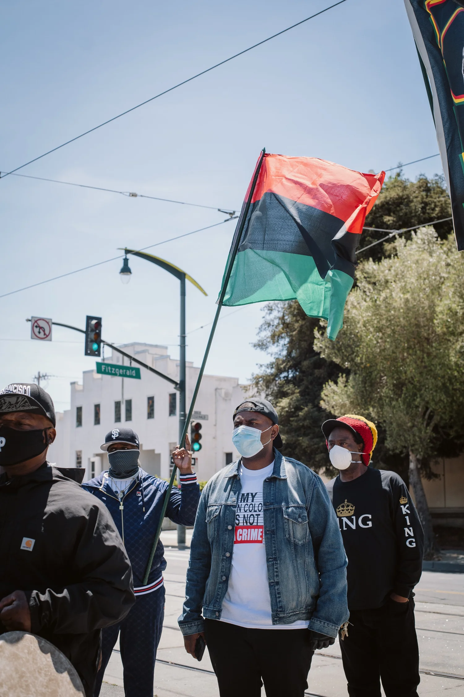 Rally participants carrying a red, black, and green flag.