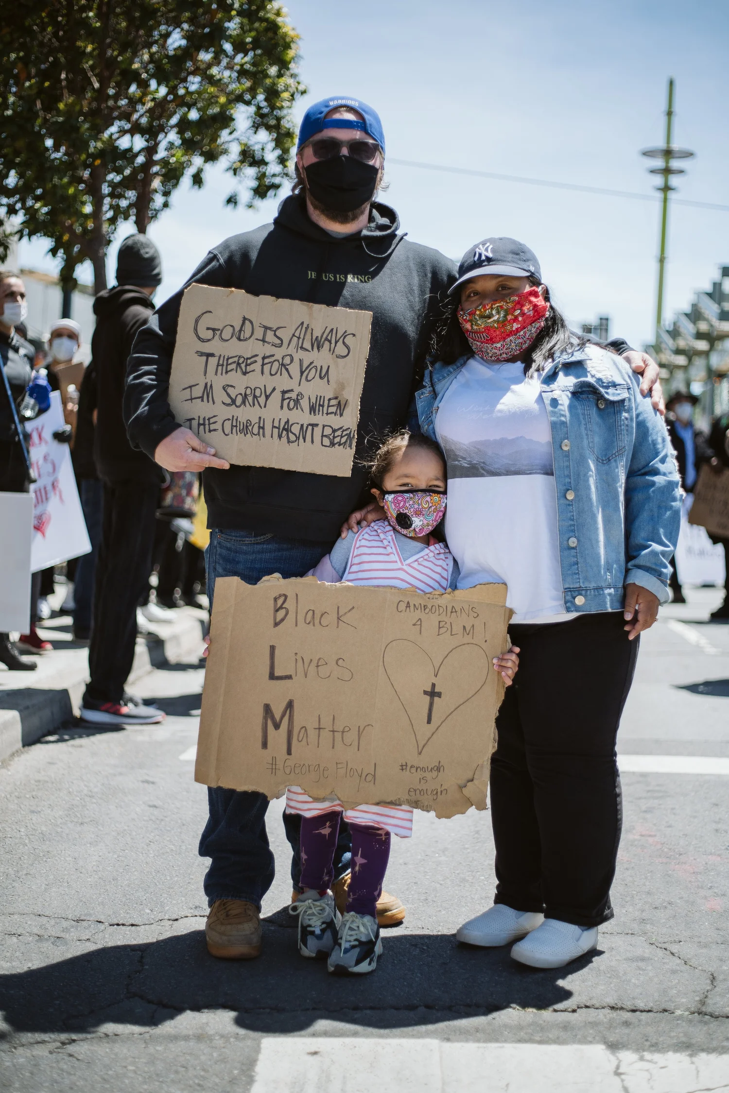 Two adults and a child posing with handmade protest signs.