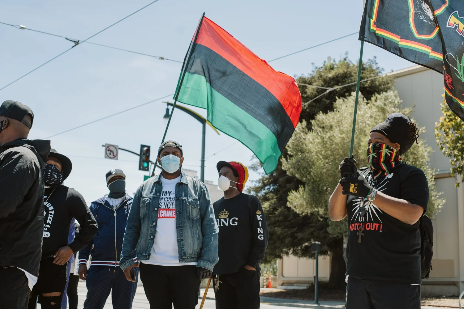 Participants standing together beneath red, black, and green flags.
