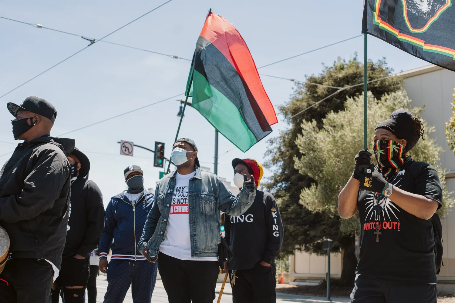 Rally participants beneath flags, with a person photographing the scene.