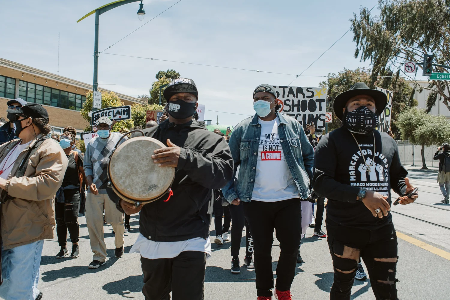 Drummer standing with other masked rally participants.