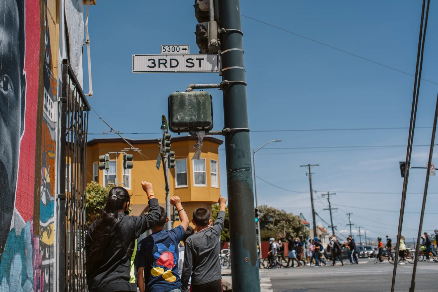 Third Street sign above bystanders watching the march.