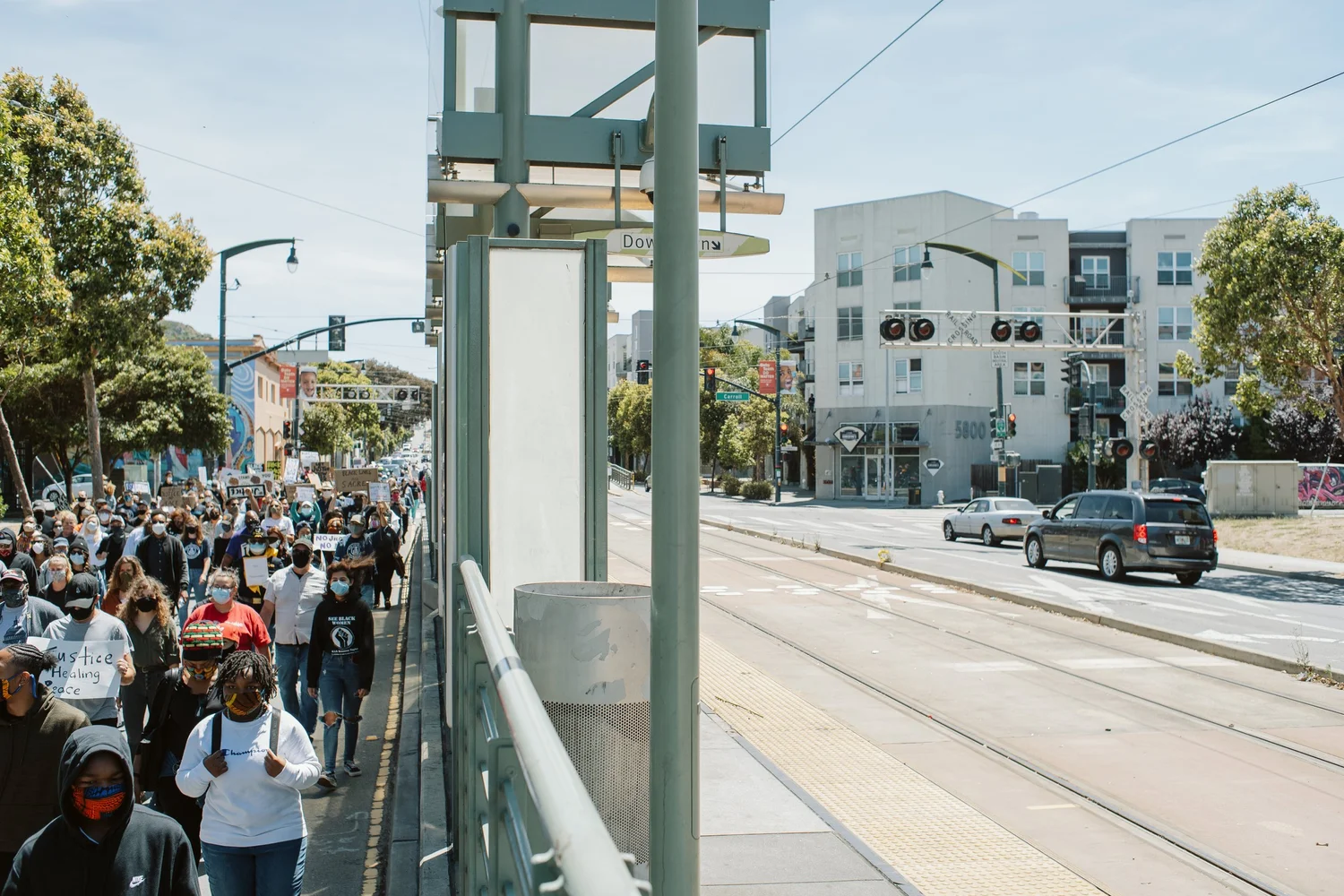 Wide view along the transit platform as marchers pass.