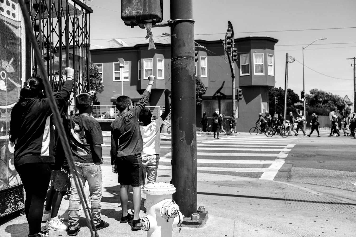 Black-and-white view of people watching the march from a street corner.