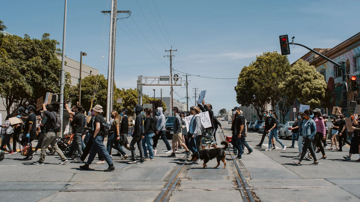 Procession crossing an intersection beside a transit platform.