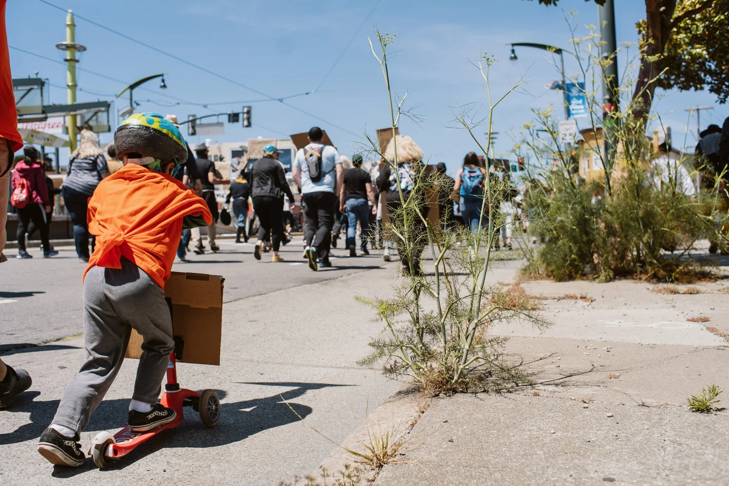 Child riding a scooter alongside the march.
