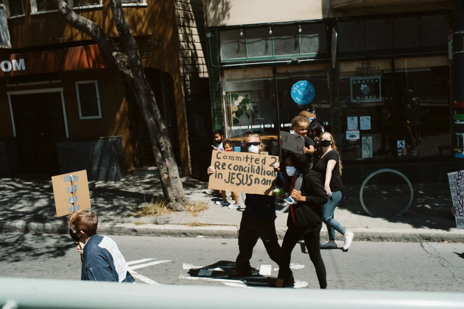 Marchers passing storefronts with handmade signs.