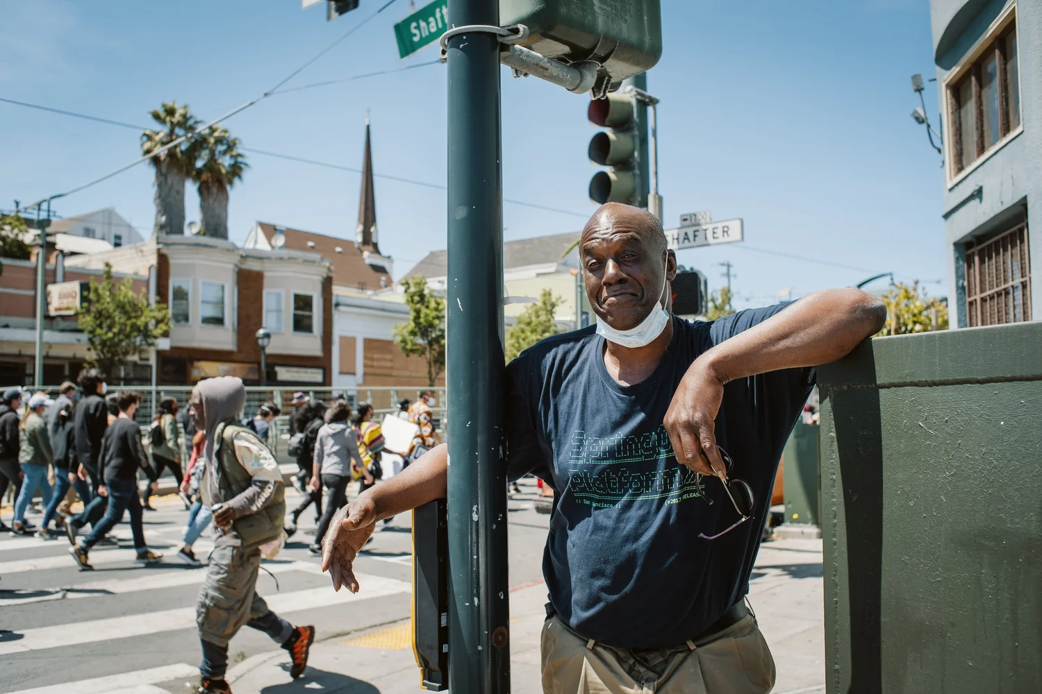 Bystander leaning against a traffic-signal box as the march passes.