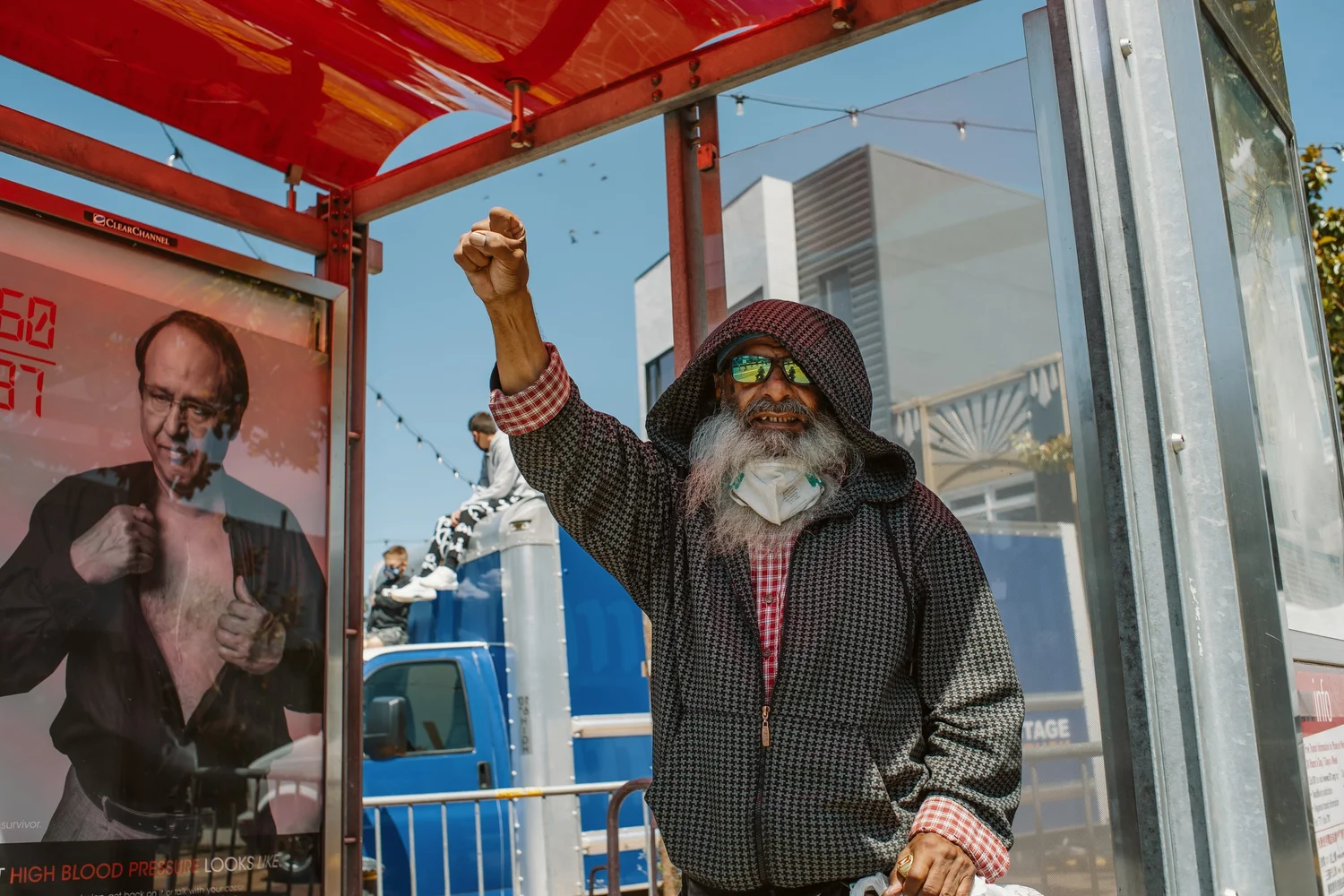 Bystander raising a fist from inside a red transit shelter.