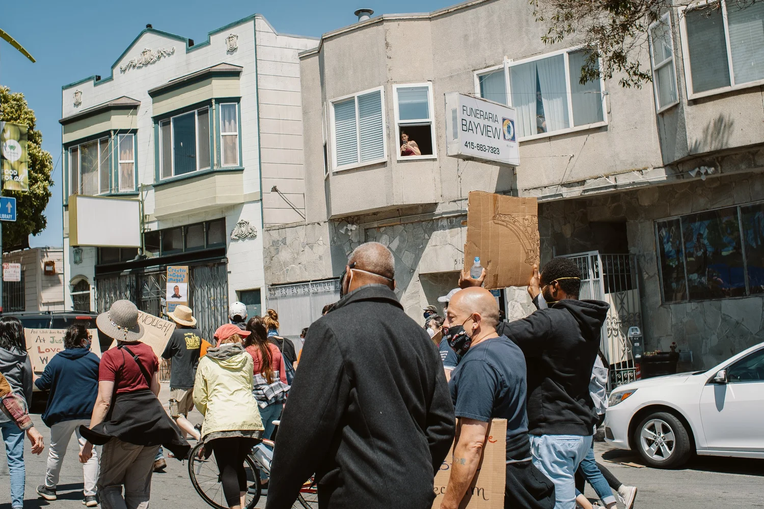 Marchers passing homes and storefronts.