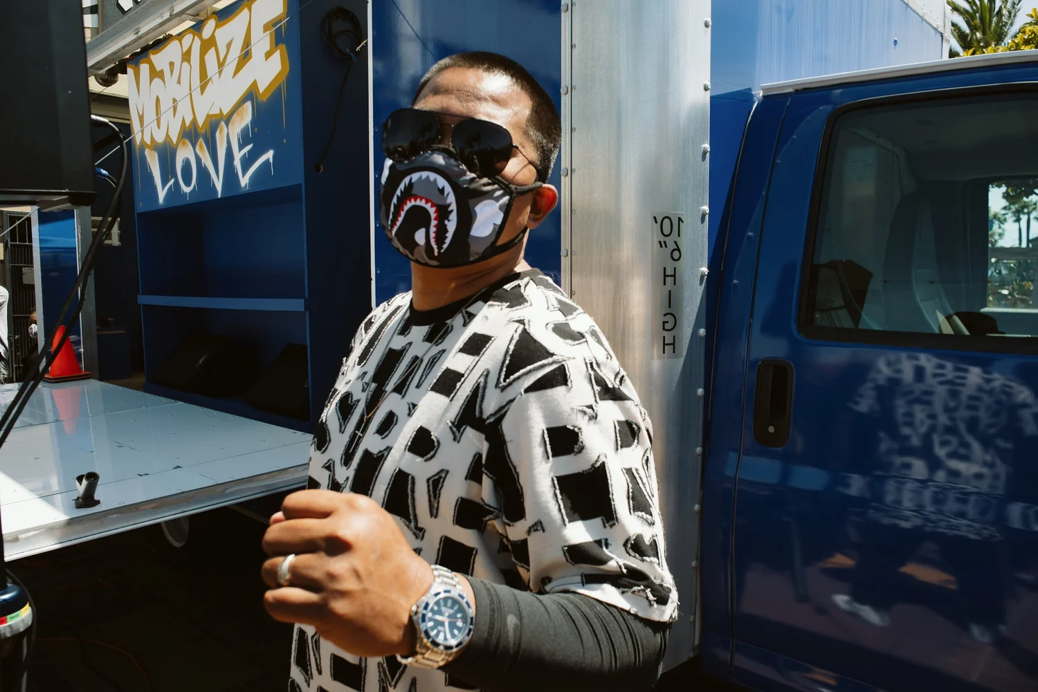 Masked participant holding a microphone beside a blue truck.
