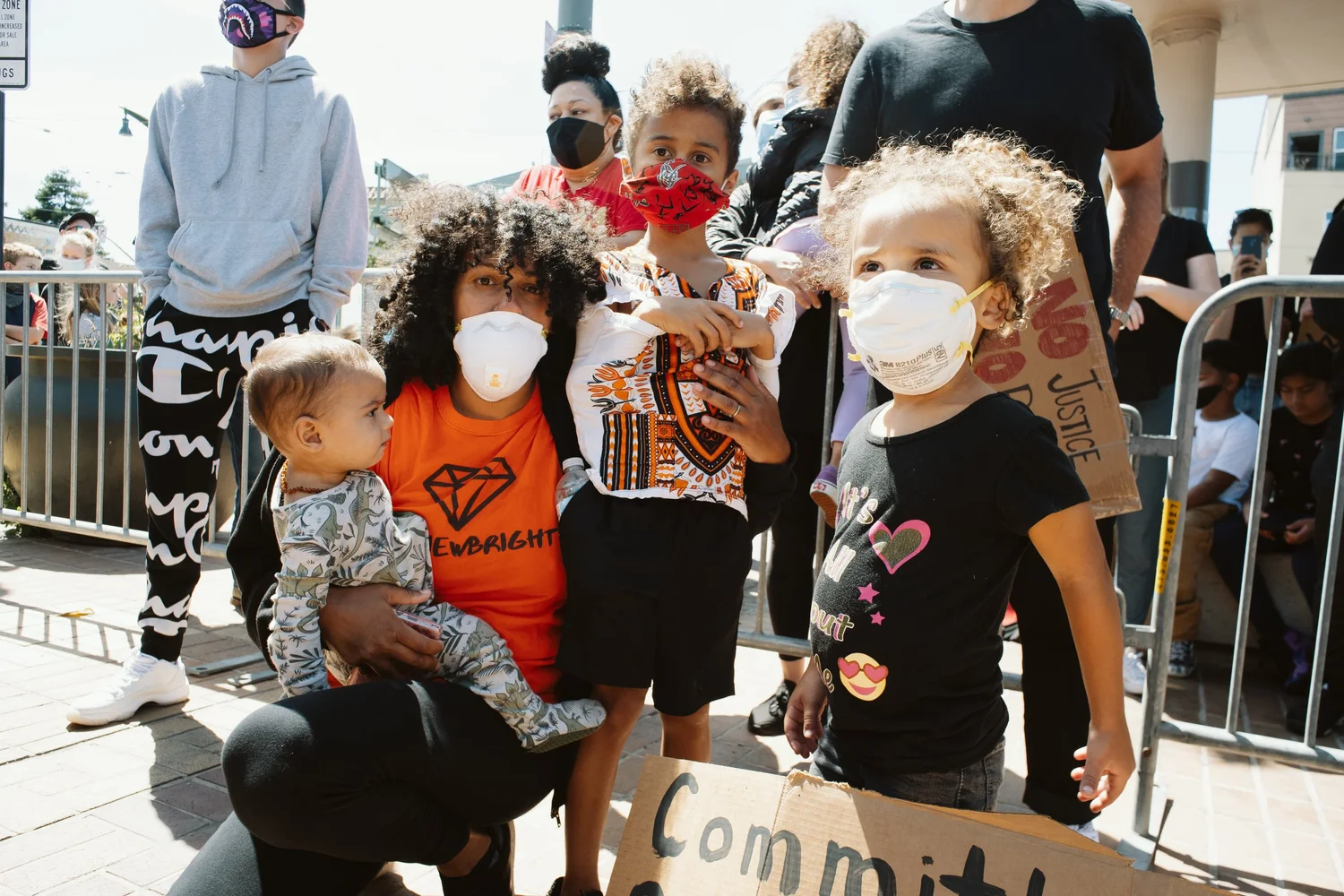 Adult holding a young child beside masked children.