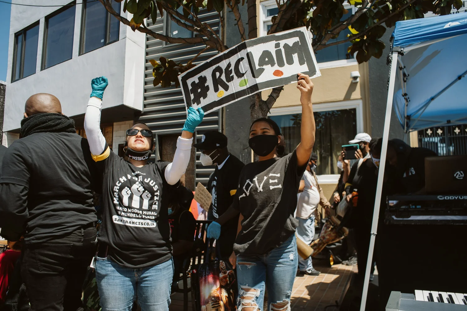 Participants lifting a Reclaim sign and raising their fists.
