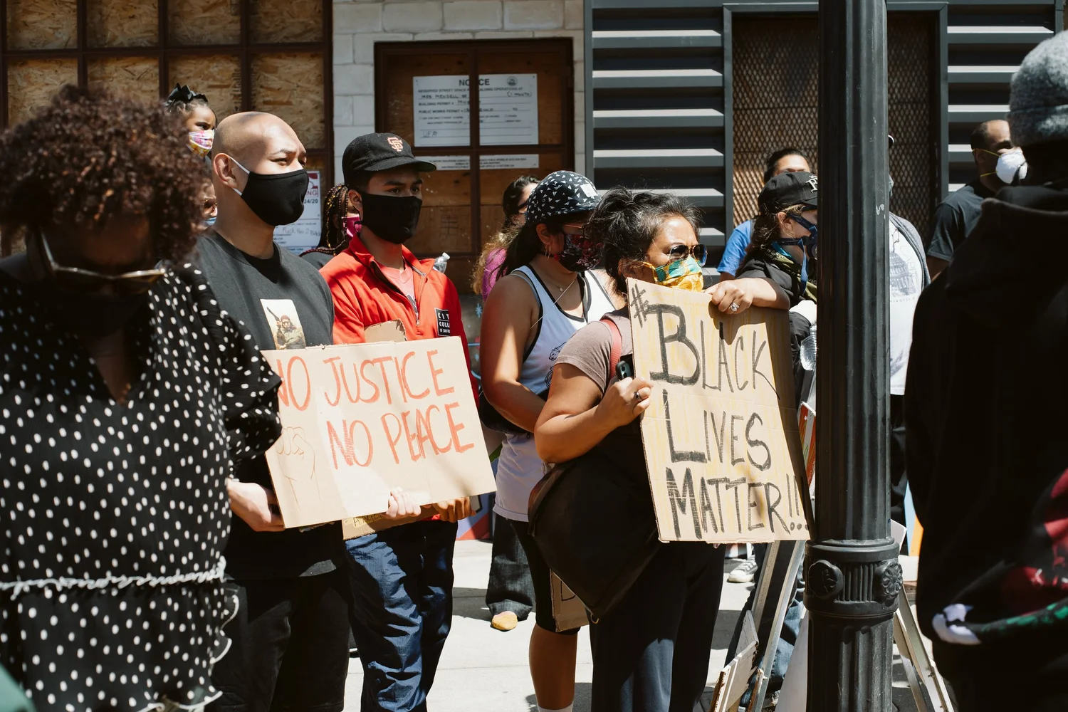 Participants holding No Justice No Peace and Black Lives Matter signs.